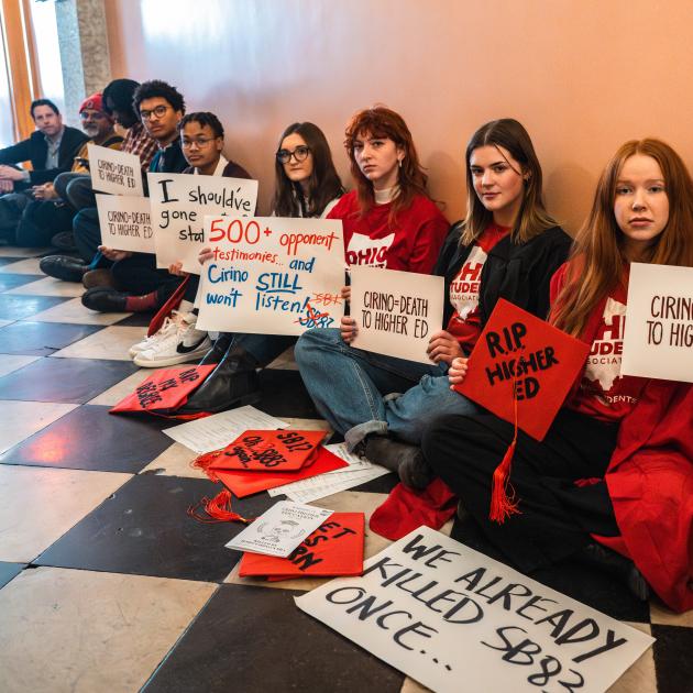 Students with protest signs sitting in a hall