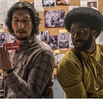 Young white man with dark hair and goatee sitting next to young black man with big afro and beard