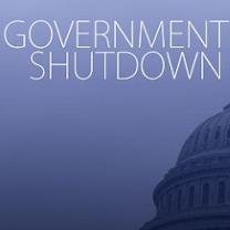 Blue background white letters saying Government Shutdown and the edge of the capitol building in DC