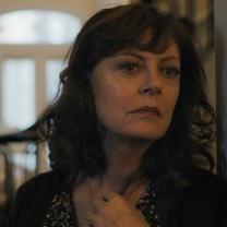 White woman with long curly brown hair looking pensive