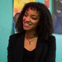 Young black woman smiling in a black suit against a colorful background