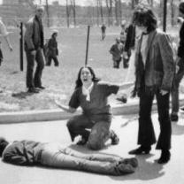 Man lying on the ground dead a woman screaming over his body, others looking on