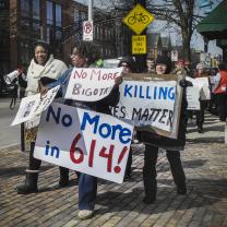 People marching down High Street holding signs that say No More in 614, no more bigotry, black lives matter.