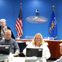 People doing a recount at tables with flags in the background