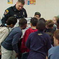 Man in police uniform surrounded by lots of small children