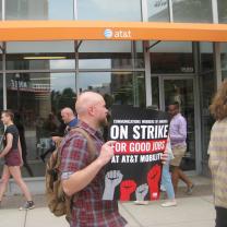 Guy in a strike protest holding a sign that says On Strike