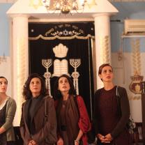 Four women staring up at something above them, standing in front of an elaborately decorated doorway