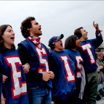 People dressed in red, white and blue with RESIST spelled out on each shirt yelliing