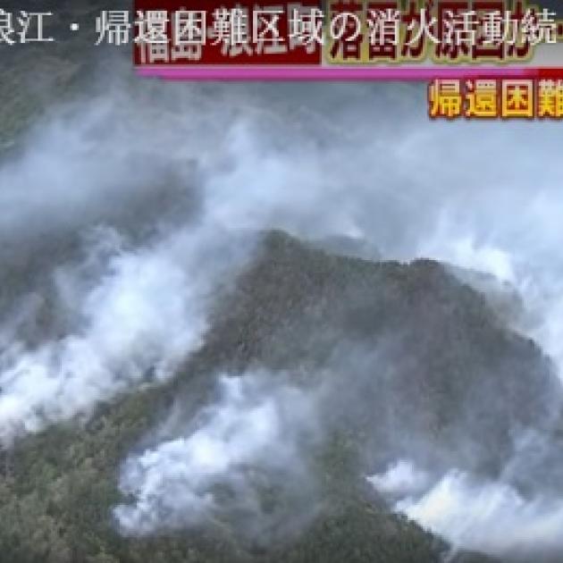 Looking down from sky at lots of smoke on ground with mountains and Japanese writing