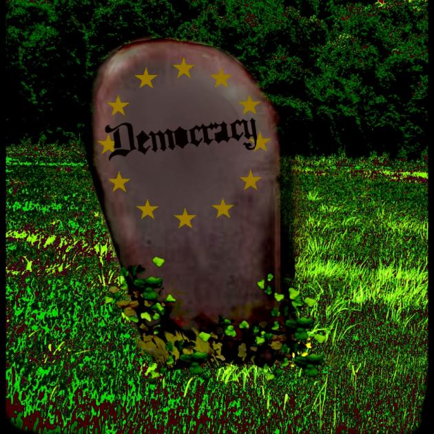 Tombstone that says Democracy on it in a grassy field