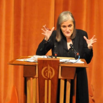 Amy gesturing with both hands at a podium