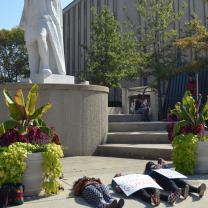 Student lying on ground beneath Columbus statue