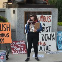 Woman in front of signs talking into a microphone