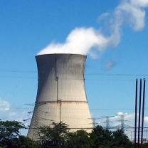 Nuclear tower with lots of white smoke coming out against a blue sky