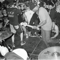 Black and white photo of black guy playing guitar with people all around dancing