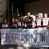 People outside with banner reading ceasefire now