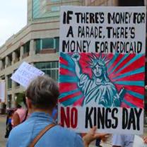 Protester holding sign saying If there's money for a parade there's money for Medicaid