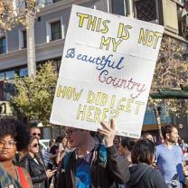 Guy holding sign saying "This is not my beautiful country, how did I get here?