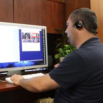 Man sitting at desk with headphones working on a computer