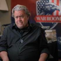 Gray haired white man by a sign reading War Room